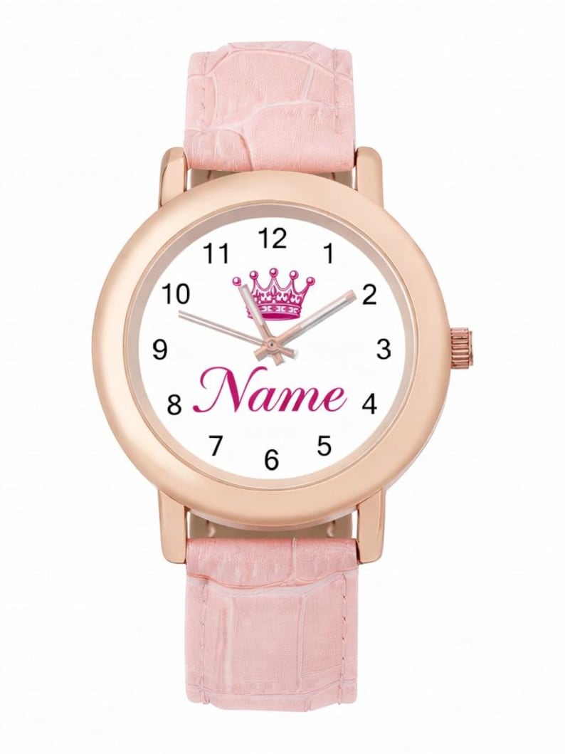May include: A rose gold wristwatch with a white face featuring a pink crown and the word "Name" in pink script. The watch has a pink leather band.