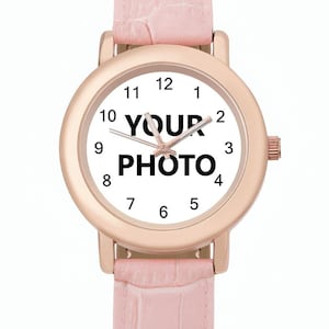 May include: A rose gold wristwatch with a white face displaying the text "YOUR PHOTO". The watch has a pink leather band. The watch face has black numerals and hands.