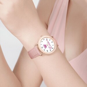 May include: A pink watch with a light pink leather band. The watch face is white with black numbers and the name "Emma" in pink script, along with a pink crown graphic. The watch is on a wrist.