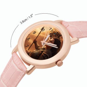 May include: A rose gold wristwatch with a light pink leather strap. The watch face features a warrior with a spear and a leopard. The watch face is 3.8cm in diameter.
