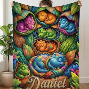 May include: A colorful dinosaur-themed blanket featuring multiple sleeping baby dinosaurs in various colors. The blanket has a patchwork design with a personalized name tag that reads "Daniel". The blanket is surrounded by leaves and flowers.