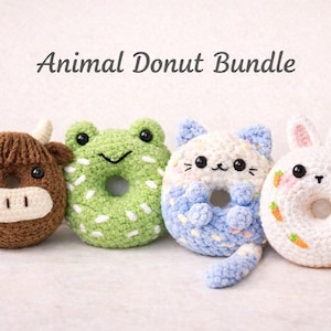 May include: Four crocheted animal donuts are displayed: a brown cow, a green frog, a blue and white cat, and a white bunny. The bunny donut has carrot accents. The text "Animal Donut Bundle" is above the donuts.