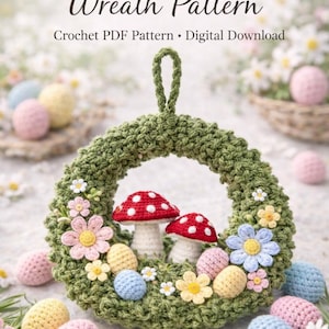Puede incluir: Una corona de Pascua tejida a ganchillo con una base verde, con acentos de hongos rojos y blancos, flores coloridas y huevos tejidos a ganchillo. El texto "Easter Mushroom Meadow Wreath Pattern" se muestra en la parte superior, con "Crochet PDF Pattern • Digital Download" debajo.