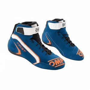 Pode incluir: Um par de sapatos de corrida de cano alto azuis com atacadores pretos, uma tira branca no tornozelo com o log&oacute;tipo OMP e detalhes em laranja. O lado do sapato exibe o texto FIRST em laranja, enquanto a biqueira apresenta o log&oacute;tipo OMP.