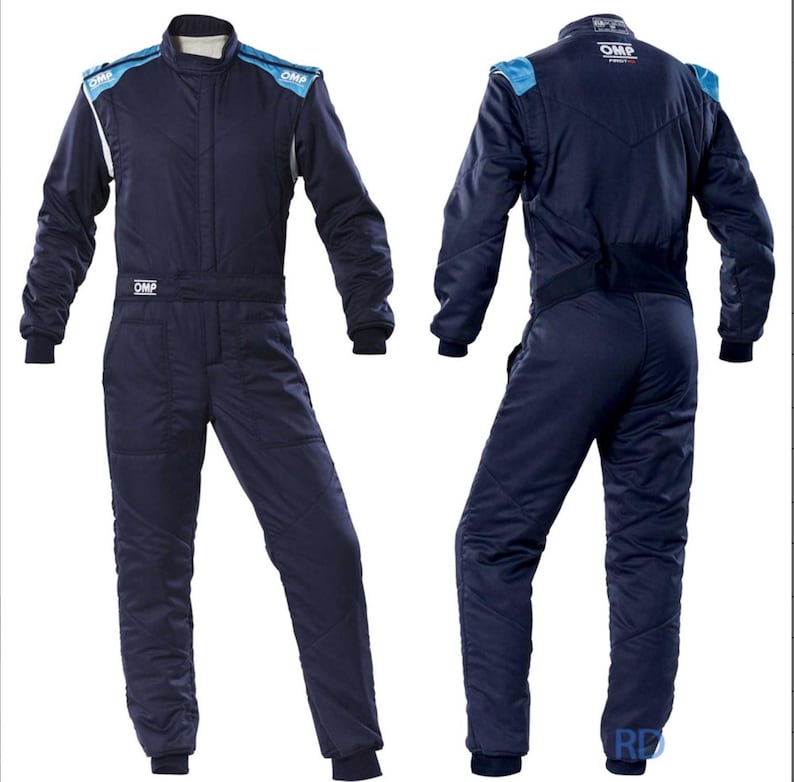 May include: Navy blue racing suit with light blue shoulder accents and white trim. The suit has long sleeves, a high collar, and the brand name "OMP" is visible. The suit is designed for motorsports.