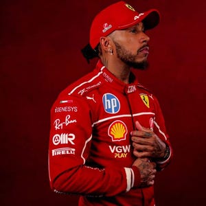 以下が含まれることがあります： Ray-Ban、Pirelli、HPなどのスポンサーロゴが入った赤いレーシングスーツとキャップ。スーツには白いアクセントと44の数字が入っています。キャップにはフェラーリのロゴが入っています。背景は無地の赤色です。