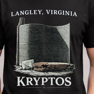 May include: A black short-sleeved t-shirt featuring a graphic of the Kryptos sculpture. The design includes the text LANGLEY, VIRGINIA at the top and KRYPTOS at the bottom, with an illustration of the curved metal plate and stone base.