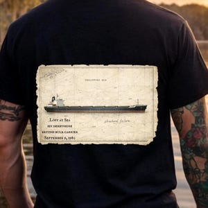 May include: Black t-shirt featuring a vintage-style graphic of a ship on a map. The graphic includes text that reads "LOST AT SEA", "MV DERBYSHIRE", "BRITISH BULK CARRIER", and "SEPTEMBER 9, 1980". The words "PHILIPPINE SEA" and "structural failure" are also present.