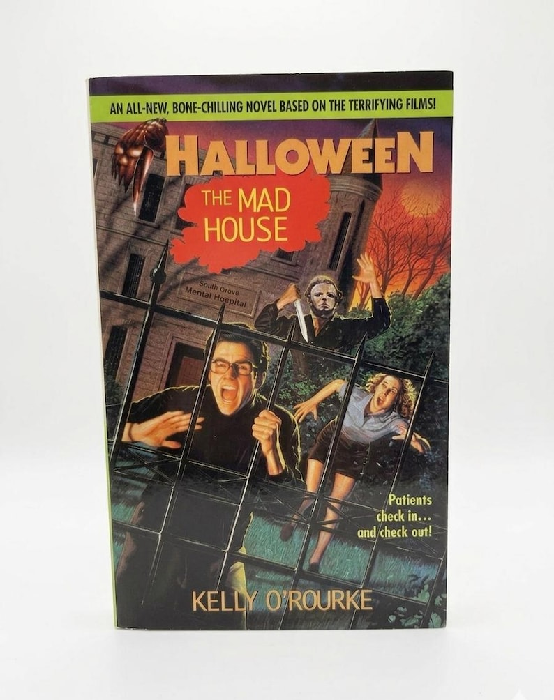 May include: A paperback book titled "Halloween: The Mad House" with a horror movie theme. The cover features a menacing figure with a knife, a spooky building, and the author's name, Kelly O'Rourke.