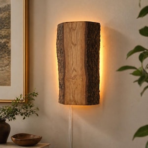 May include: A wooden wall sconce crafted from a section of a tree trunk. The natural wood grain is visible, with a rough bark edge. The sconce emits a warm glow. The sconce is approximately 30 cm tall.