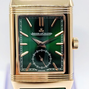 Puede incluir: Un reloj de pulsera rectangular dorado con esfera verde y correa de cuero verde. La esfera del reloj presenta agujas e indicadores dorados, con el nombre de la marca "JAEGER-LECOULTRE". El reloj est&aacute; marcado "SWISS MADE".