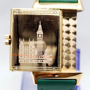 Puede incluir: Reloj de pulsera dorado con correa de cuero verde. La esfera del reloj presenta un grabado detallado del Big Ben y el Parlamento. El reloj tiene una esfera rectangular y una correa dorada.