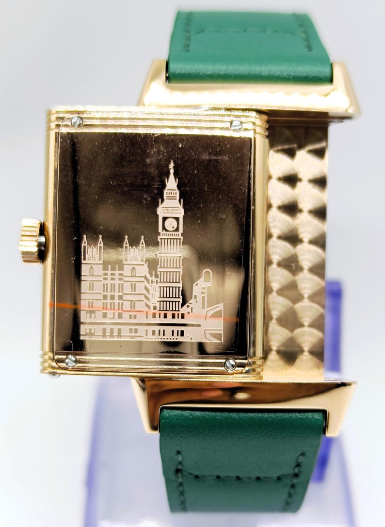 Puede incluir: Reloj de pulsera dorado con correa de cuero verde. La esfera del reloj presenta un grabado detallado del Big Ben y el Parlamento. El reloj tiene una esfera rectangular y una correa dorada.
