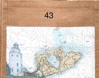 May include: A natural burlap tote bag with a nautical chart of Montauk, NY, and a lighthouse illustration. The text "Montauk, NY" and coordinates are printed below the chart. The number "43" is printed on the top.