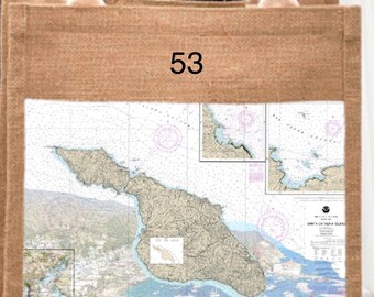 May include: A natural burlap tote bag featuring a map of Catalina Island. The map includes nautical charts and coordinates. The bag has cream-coloured handles and the number "53" printed on the top.