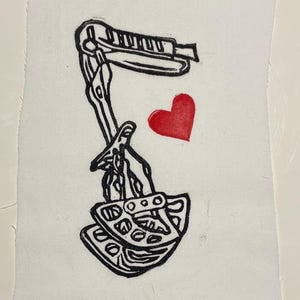 May include: Black and white linocut print on paper featuring a stylized image of a stapler, a pair of scissors, and a red heart. The print is on a white background.