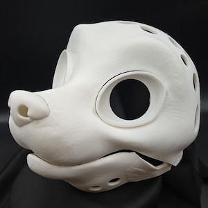 Könnte beinhalten: Ein weißer, 3D-gedruckter Fursuit-Kopfrohling mit großen Augenöffnungen, einer markanten Schnauze und Belüftungslöchern. Die Maske ist für die individuelle Gestaltung und Bemalung eines einzigartigen Charakters konzipiert.