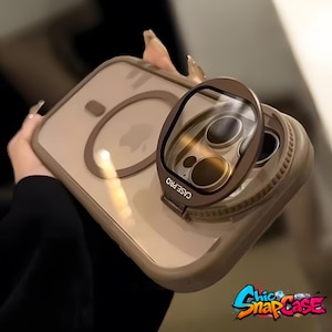 May include: A clear phone case with a brown border and a matching camera lens protector. The lens protector is labeled "CASE PRO" and is attached to the phone case. The case is held by a person.