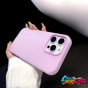 May include: A light purple phone case with a camera cutout featuring three lenses and a flash. The case is held in a hand. The logo "Chic SnapCase" is in the bottom right corner.