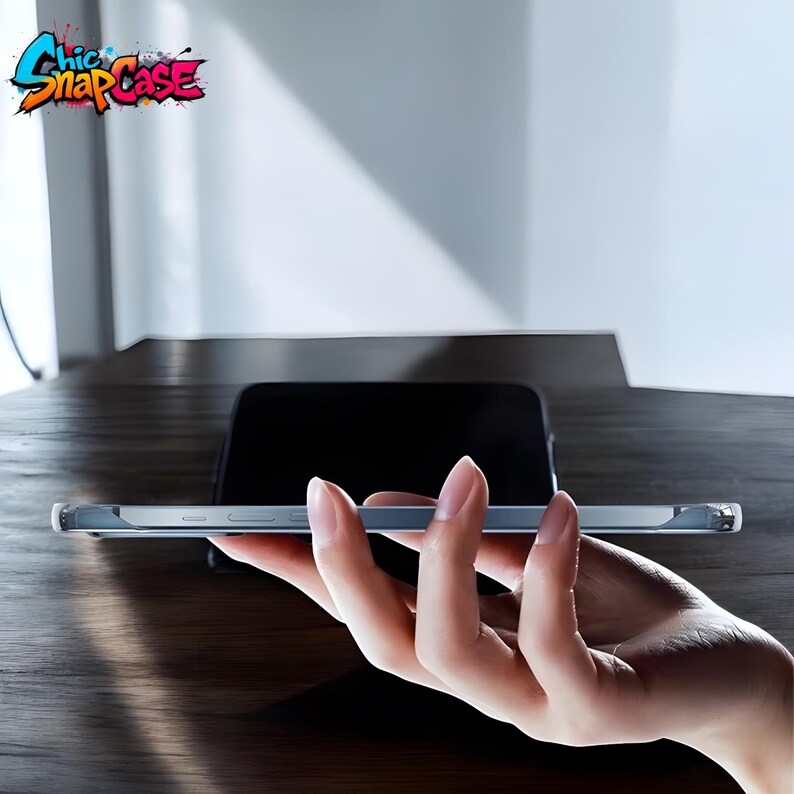May include: A clear phone case held in a hand, with a black phone in the background. The case has a slim profile and a transparent design. The logo "Chic Snap Case" is visible in the upper left corner, featuring colorful graffiti-style lettering.