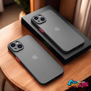 Può includere: Due custodie grigie per smartphone con bordi neri e accenti rossi sono esposte su una superficie di legno. Le custodie hanno un design elegante con il logo Apple visibile. Le custodie sono posizionate su una scatola nera. Il logo Chic Snap Case si trova in basso a destra.