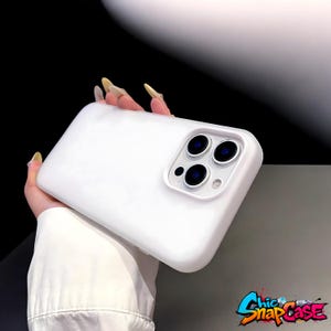 May include: A white phone case with a triple-lens camera cutout. The case has a smooth, matte finish and is designed to protect a smartphone. The Chic Snap Case logo is visible in the bottom right corner.