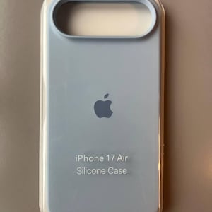 Könnte beinhalten: Eine hellblaue Silikonhülle für ein iPhone 17 Air. Die Hülle hat einen Ausschnitt für die Kamera und die Tasten und zeigt das Apple-Logo. Der Text "iPhone 17 Air Silicone Case" ist auf der Hülle aufgedruckt.