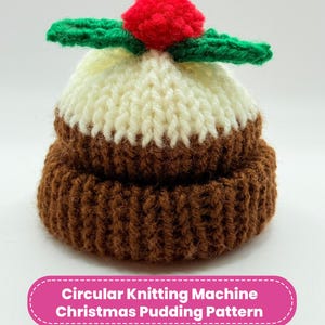May include: A knitted Christmas pudding with a red pom-pom and green leaf accents. The pudding is brown, cream, and white. The image includes the text "Circular Knitting Machine Christmas Pudding Pattern".