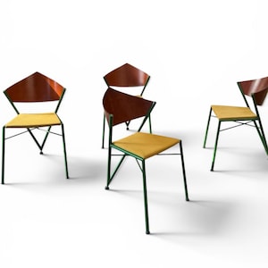 Peut inclure: Un ensemble de quatre chaises dotées de structures en métal vert foncé, d'assises rembourrées jaunes et de dossiers en bois incurvés. Chaque chaise possède quatre pieds fins avec de petits embouts et une structure reliant l'assise au dossier.