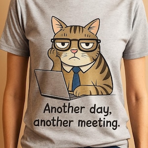 Peut inclure: T-shirt gris avec un chat de dessin animé portant des lunettes et une cravate, appuyé sur un ordinateur portable. Le chat a une expression sérieuse. Le texte "Another day, another meeting" est imprimé en dessous.