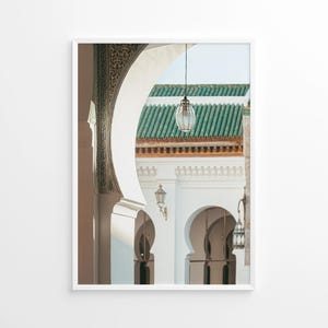 May include: Framed print of an architectural scene featuring arched doorways and a green tiled roof. A decorative hanging lantern is suspended in the center. The building has white walls and ornate details, creating a serene and inviting atmosphere.