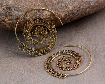 May include: Two gold-colored spiral earrings with intricate, openwork designs. The earrings have a circular shape with a central spiral and delicate, decorative edges. The earrings are displayed on a neutral, textured surface.