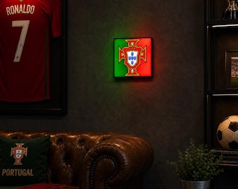 May include: A square, wall-mounted LED light box featuring the national emblem of Portugal, displayed with a green and red background. The emblem includes a central white shield with blue quinas and a yellow armillary sphere border.