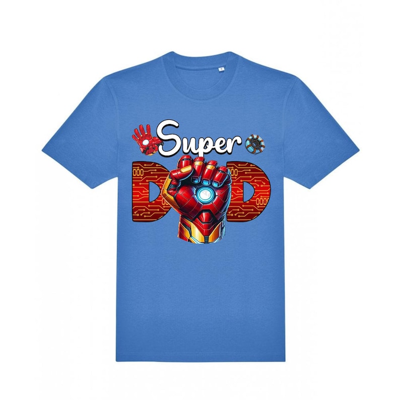 May include: A light blue t-shirt with a graphic design. The design features the words "Super Dad" with a red and gold Iron Man-style hand and the letter "D" in a circuit board pattern. The shirt is a crew neck.