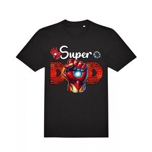 May include: Black t-shirt with a graphic of an Iron Man-style hand in a fist, with the words "Super Dad" in white and red. The design includes a circuit board pattern and a glowing blue center.
