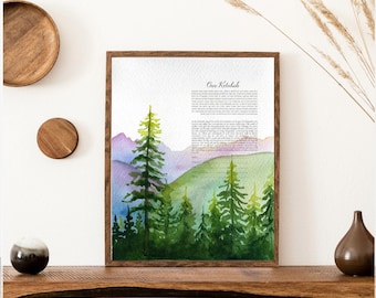 May include: A framed Ketubah print featuring a watercolor landscape of green pine trees and purple mountains. The text "Our Ketubah" is printed at the top, followed by paragraphs of text and blank lines for signatures at the bottom of the paper.