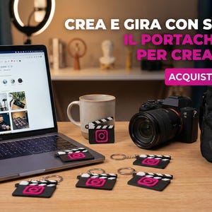 Può includere: Un laptop che mostra una pagina Instagram è su una scrivania di legno, circondato da una fotocamera, una tazza di caffè e diversi portachiavi neri con un logo Instagram rosa e un design a ciak. Il testo recita "CREA E GIRA CON STILE. IL PORTACHIAVI PER CREATOR. ACQUISTA ORA!"