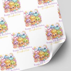 Peut inclure: Papier cadeau avec un motif répétitif de raviolis mignons et colorés dans des paniers vapeur en bambou, entourés de ballons, d'arcs-en-ciel et de beignets. Le texte "Happy 9th Birthday Arabella" est écrit en lettres violettes et dorées.