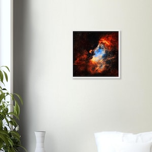 May include: A square wall art print featuring a vibrant nebula with swirling clouds of deep red, bright orange, and glowing blue gas set against a dark black space background, framed in a simple white border for a clean display.