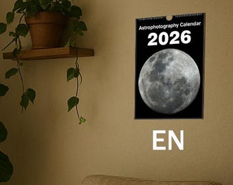 Könnte beinhalten: Gemütliches Wohnzimmer in neutralen Farben. Ein Holztisch beherbergt Bücher und eine Tasse. Ein beiger Sessel hat eine cremefarbene Decke. Ein 2026-Kalender mit Mondbild hängt an der Wand. Topfpflanzen sorgen für einen Hauch von Natur.