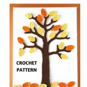 Op de afbeelding: Haakpatroon voor een bruine boom met gele en oranje bladeren. De tekst "CROCHET PATTERN" staat onder de boom. De afbeelding is op een witte achtergrond met een bruine lijst.