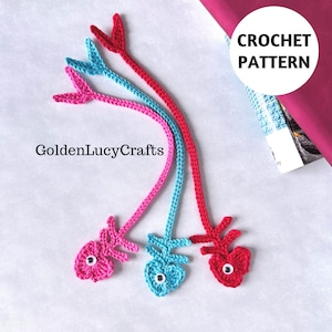 May include: Three handmade crochet fish bookmarks in pink, blue, and red. Each bookmark features a fish-shaped design with a tail and eye detail. The image includes the text "GoldenLucyCrafts" and "CROCHET PATTERN".