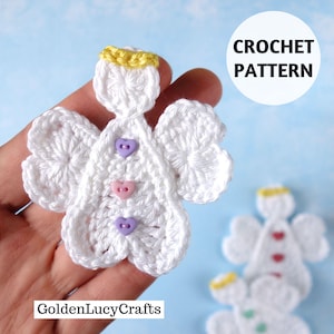 May include: A white crocheted angel ornament with a yellow halo and three small heart-shaped buttons in purple, pink, and purple down the center. The text CROCHET PATTERN and GoldenLucyCrafts are visible on the image.