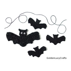 May include: Four black crocheted bats with white eyes. The bats are of different sizes and are arranged on a white background. There is a black string in the background.
