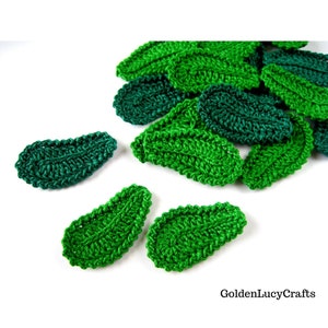 May include: A collection of green crocheted leaf shapes. The leaves are made with a textured stitch and have a slightly oval shape.