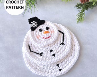 Könnte beinhalten: Gehäkeltes Schneemann-Untersetzer-Set. Der Schneemann ist weiß mit schwarzem Hut, Armen und Knöpfen. Er hat eine Karottennase, rosige Wangen und einen lächelnden Mund. Der Text "CROCHET PATTERN" befindet sich in einem weißen Kreis.