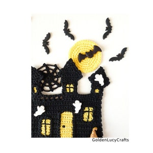 May include: A crocheted black and yellow Halloween haunted house with a yellow crocheted moon and black bats. The house has a spider web, windows, and a door. There are white ghost buttons on the house.