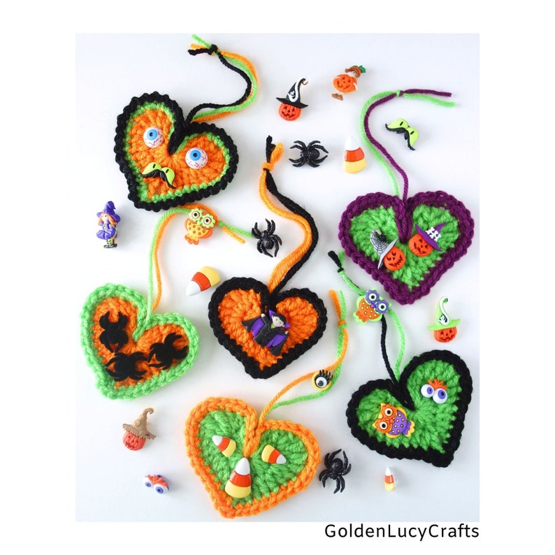 May include: Five crocheted Halloween-themed hearts with various embellishments, including googly eyes, spiders, bats, and candy corn. The hearts are in shades of green, orange, purple, and black. The text "GoldenLucyCrafts" is visible at the bottom of the image.