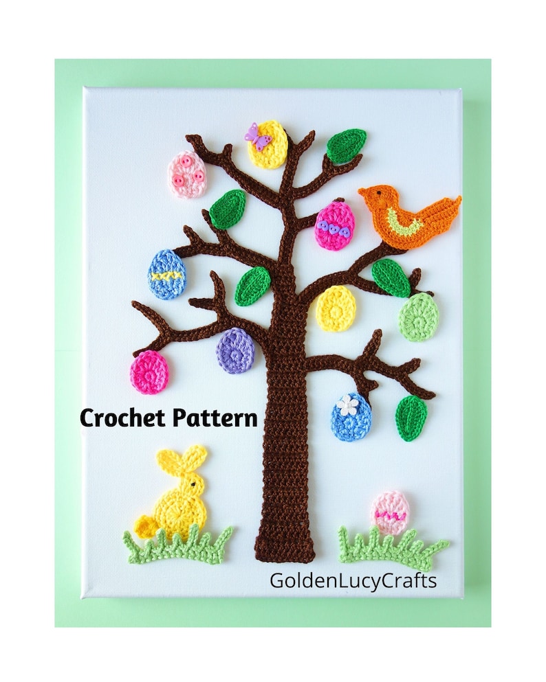 Puede incluir: Arte de pared de &aacute;rbol de Pascua tejido a crochet con un tronco marr&oacute;n, hojas verdes y huevos de colores. Un conejito tejido a crochet amarillo se sienta en la hierba debajo del &aacute;rbol. El texto "Crochet Pattern" y "GoldenLucyCrafts" son visibles en el lienzo blanco.