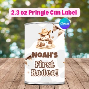 May include: A 65g Pringle can label with a cowboy theme. The label features a two-tiered cake with a cowboy hat, cow print accents, and the text "NOAH'S First Rodeo!" in brown. The background is white.